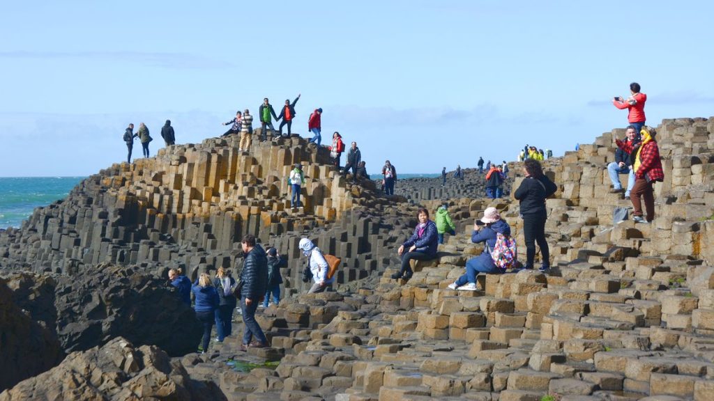Turister vid Stenformationerna Giant's Causeway i Nordirland