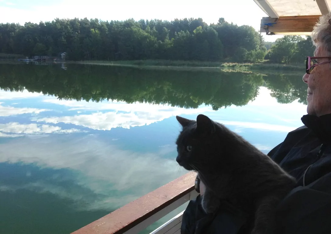 Hustrun Birgitta och katten blickar ut över relingen på husbåten