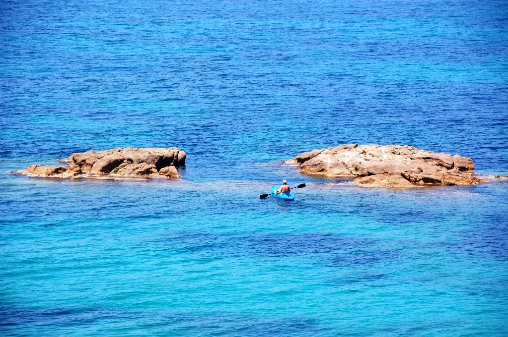 En blå kanot glider genom det blå vattnet