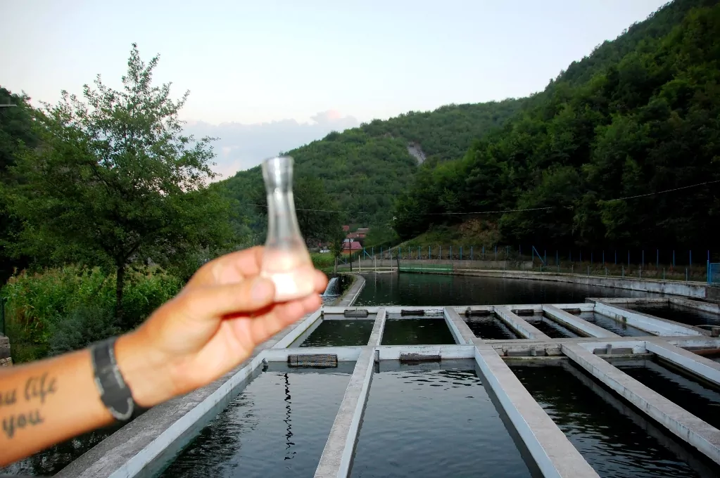 Peter håller upp ett glas raki (plommonbrännvin) framför restaurangens fiskodling