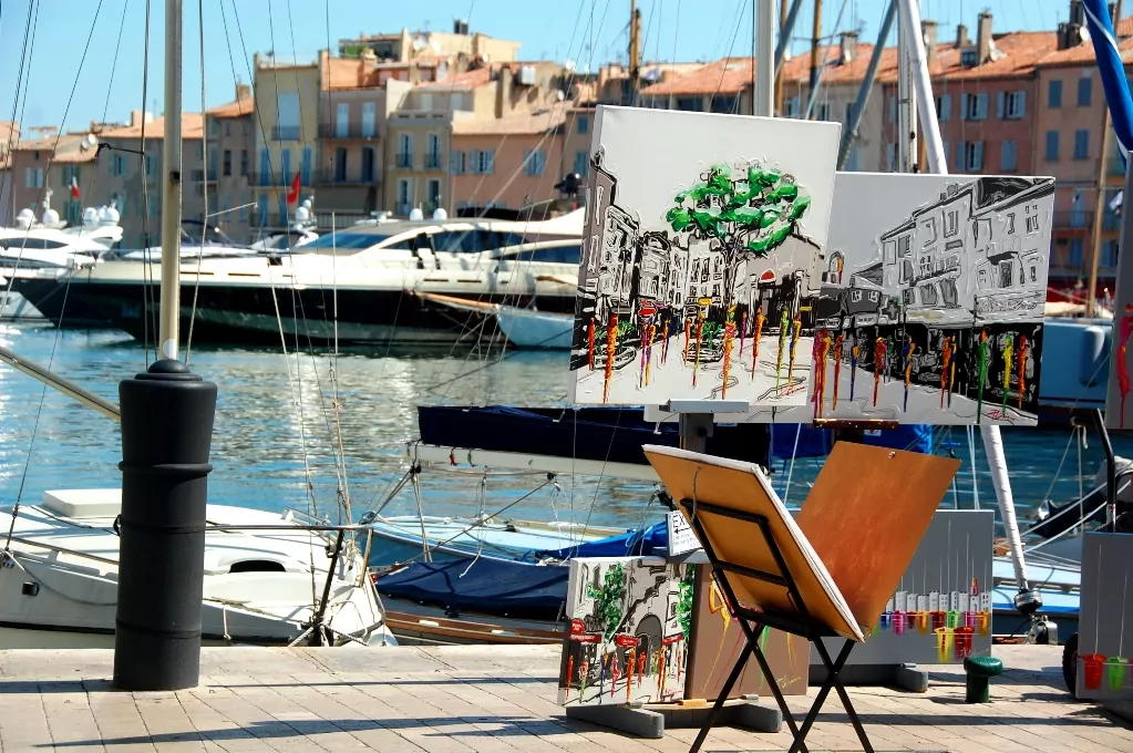 Vid hamnen står flera konstnärer och målar och säljer tavlor